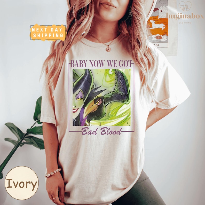 A woman wearing a white t-shirt with a graphic design featuring a character from the Disney movie "Bad Blood".