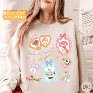 A woman wearing a white sweatshirt with various cartoon-style illustrations and text on it.