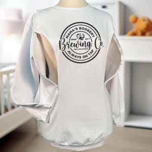 May include: White sweatshirt with a round black graphic that reads "Mama's Boobery Brewing Co. Open 24/7 Two Locations Always on Tap." The sweatshirt has a zipper opening on the front.