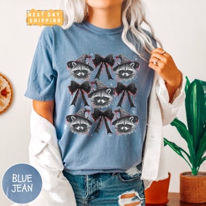 a woman wearing a blue shirt with raccoons on it