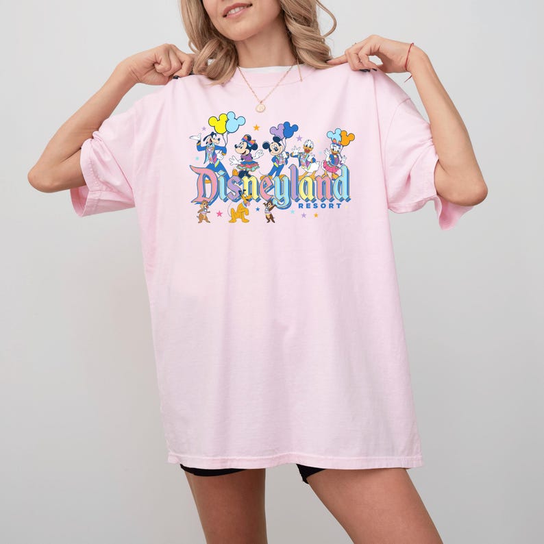 a woman wearing a pink disneyland shirt