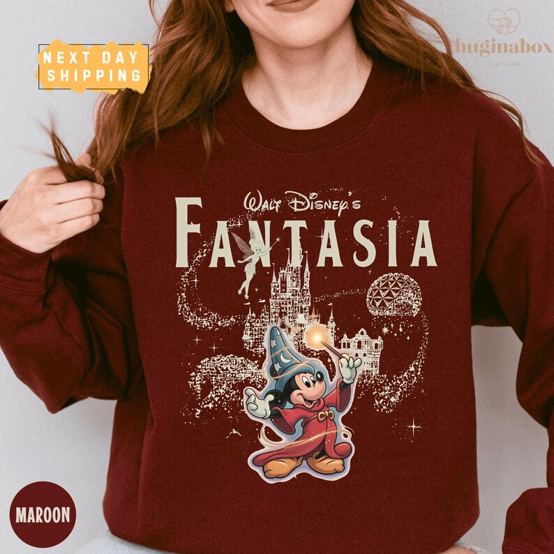 A woman wearing a maroon sweater with a Disney-themed design featuring Mickey Mouse and the title "Fantasia".