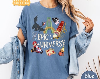May include: Blue jean-colored t-shirt with the words "Epic Universe" and various cartoon graphics. The graphics include a dragon, a roller coaster, Mario in a kart, and a dessert. The shirt has short sleeves.