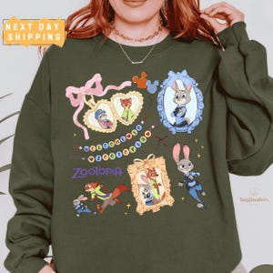 A person wearing a green sweatshirt with various cartoon animal characters and a "Zootopia" theme printed on it.