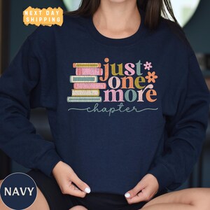 a woman wearing a navy shirt with a stack of books on it