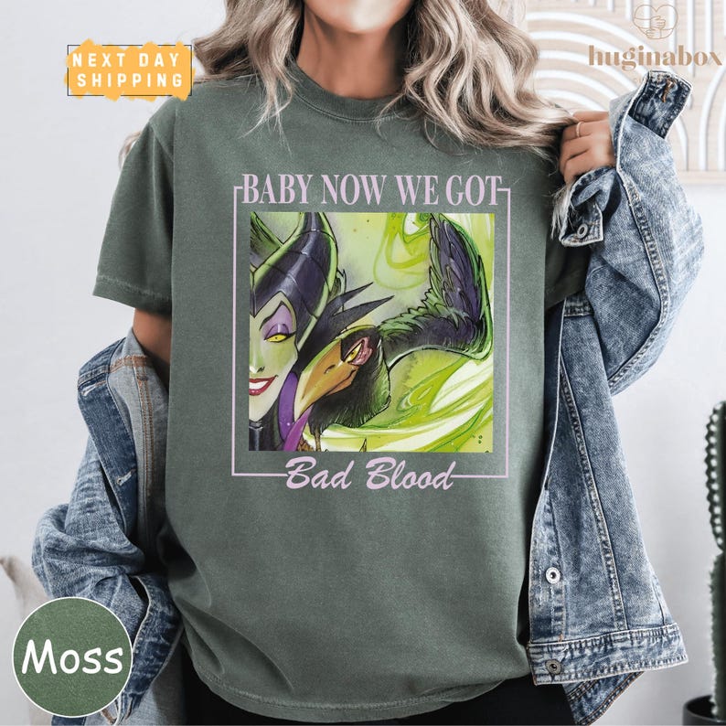 A person wearing a green t-shirt with a graphic design featuring a character from the Disney film "Bad Blood".