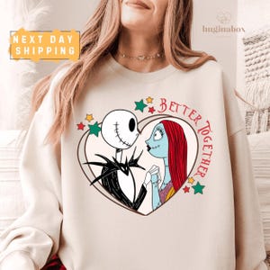 A woman wearing a white sweatshirt with a graphic design featuring a skeleton and a woman's face, along with the text "Better together".