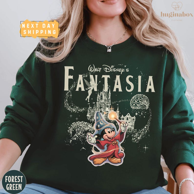 A woman wearing a green sweatshirt with a Disney-themed design, including a character and a castle.