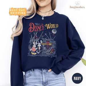 A woman wearing a navy blue sweatshirt with a Disney World-themed graphic printed on it.