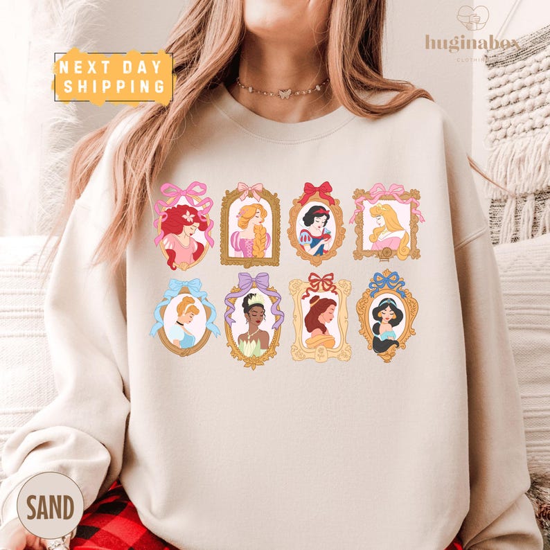 A woman wearing a white sweatshirt with a graphic of various Disney princesses in frames.