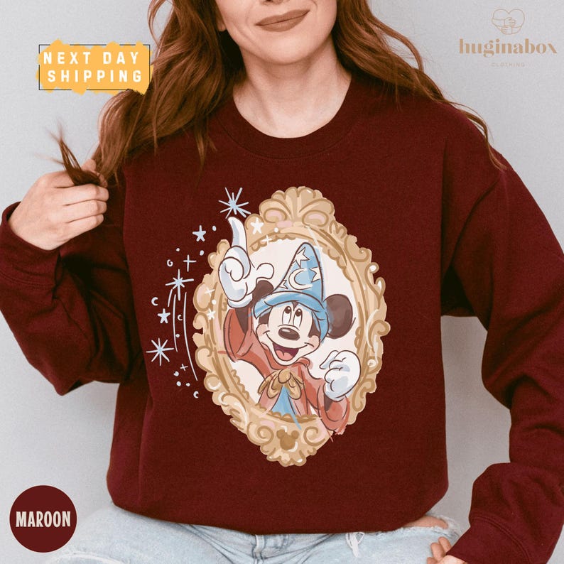 A woman wearing a burgundy sweater with a Mickey Mouse design and a framed image of Mickey Mouse.