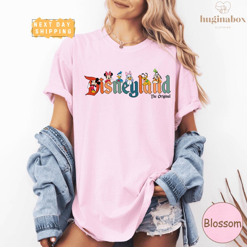 A woman wearing a pink t-shirt with the Disney logo and text, along with a denim jacket, posing against a white background.