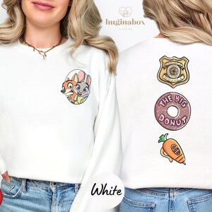 A woman wearing a white sweater with cartoon characters and a donut on the back.