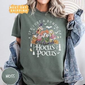 a woman wearing a green t - shirt with the words hocus pocus on