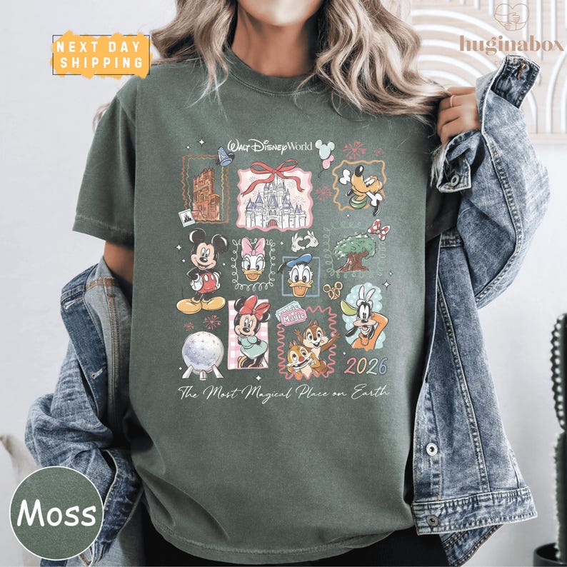A person wearing a green t-shirt with a collage of Disney characters and a date printed on it.