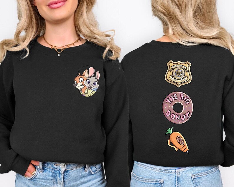 A woman wearing a black sweater with cartoon characters and a police badge on the back.
