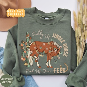 May include: A green sweatshirt with a brown horse decorated with Christmas lights and the text "Giddy Up Jingle Horse Pick Up Your Feet".