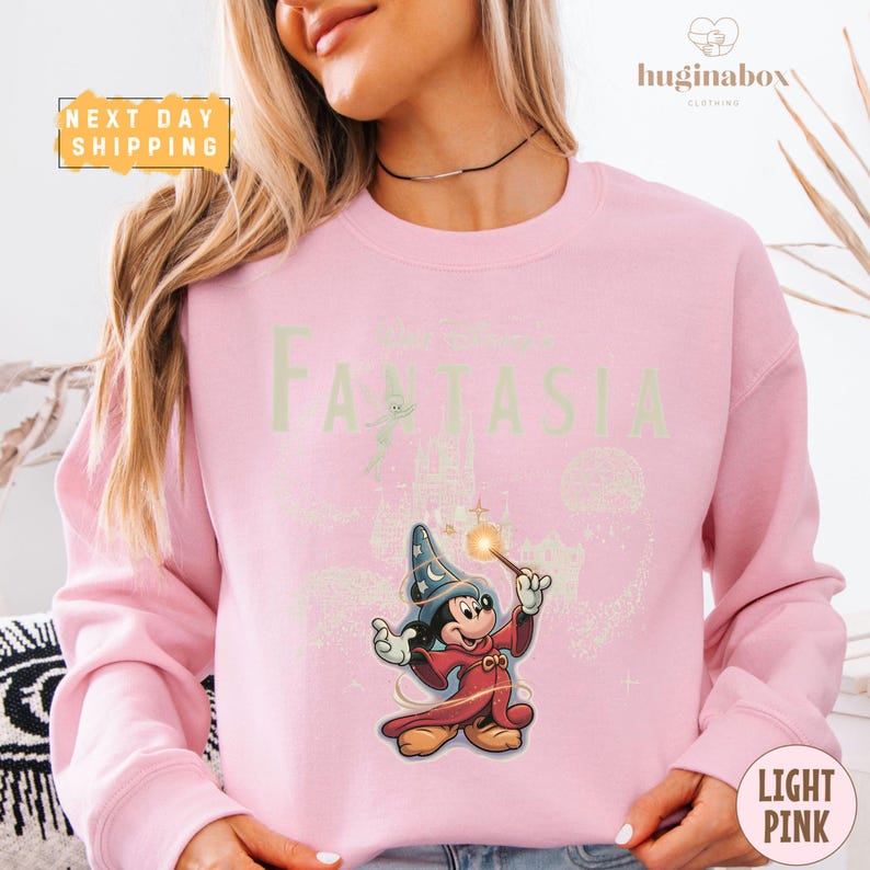 A woman wearing a pink sweatshirt with a cartoon character and text printed on it.