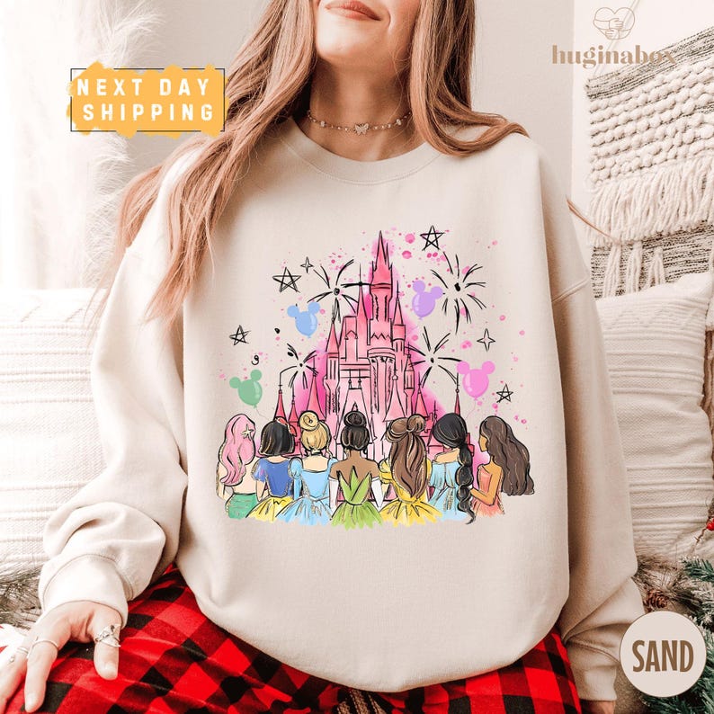 A woman wearing a white sweatshirt with a colorful illustration of a castle and a group of women in various outfits.