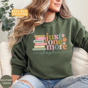 a woman sitting on a couch wearing a green sweatshirt