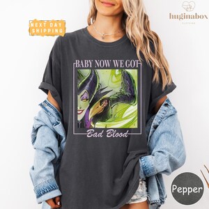 A woman wearing a black t-shirt with a graphic design featuring a character from the Disney movie "Bad Blood".