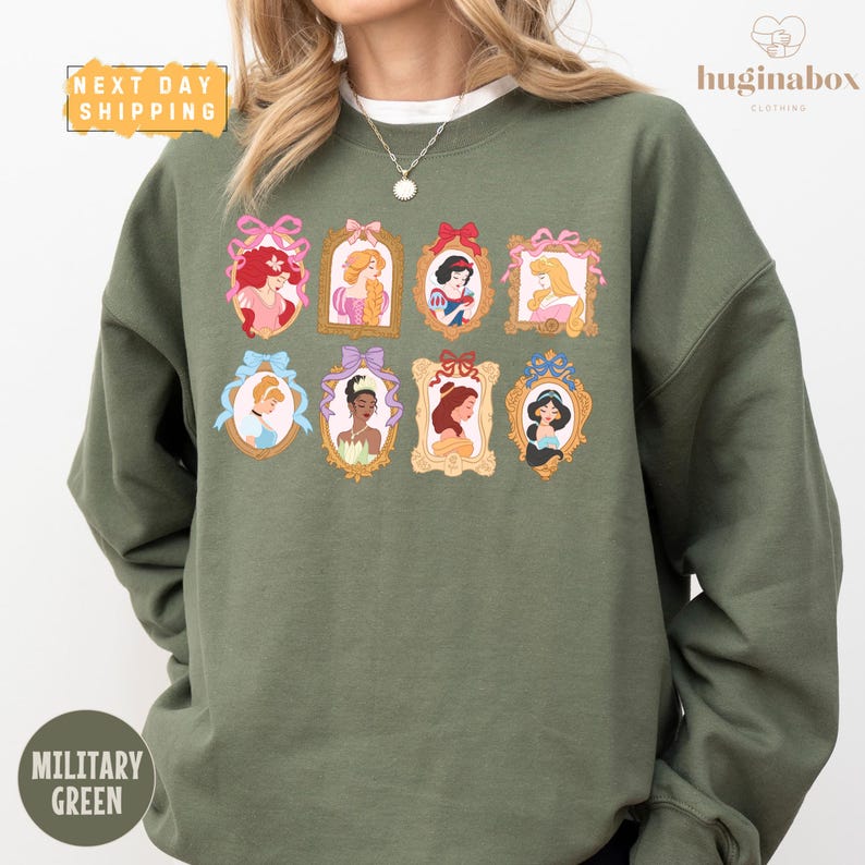 A woman wearing a green sweatshirt with a collage of illustrations of Disney princesses.
