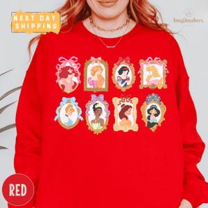 A woman wearing a red sweater with illustrations of various Disney princesses on it.