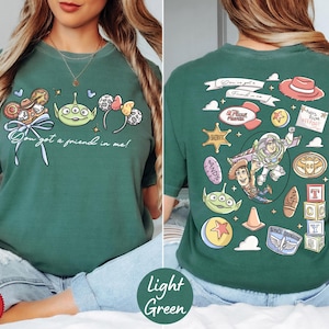 A woman wearing a green t-shirt with various cartoon characters and icons printed on it, including a character from the Toy Story franchise.