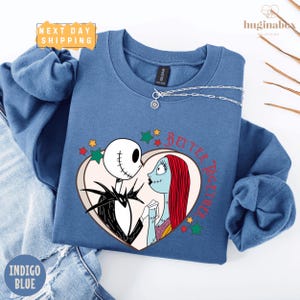 A blue sweatshirt with a graphic design featuring the characters Jack Skellington and Sally from the movie "The Nightmare Before Christmas".