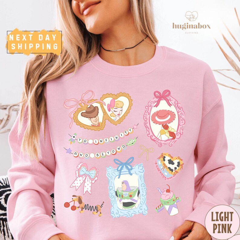 A woman wearing a pink sweatshirt with various cartoon-style illustrations and text on it.