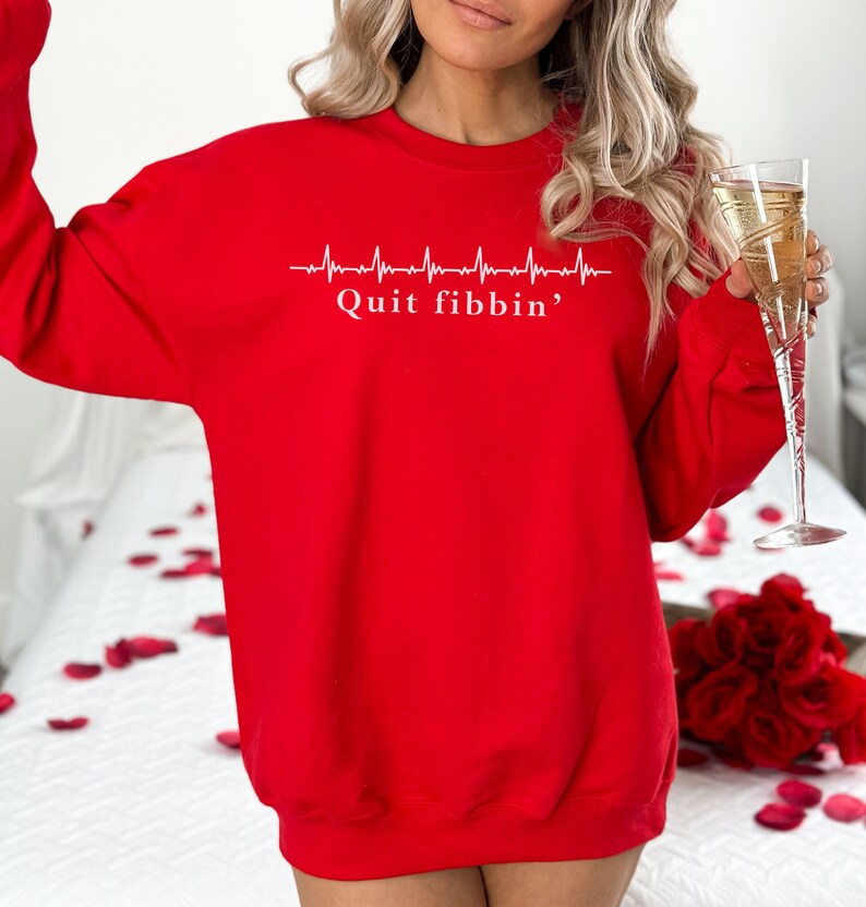 a woman in a red sweatshirt holding a glass of champagne