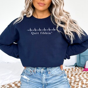 a woman with blonde hair wearing a sweatshirt and jeans