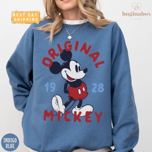 A woman wearing a blue sweatshirt with a graphic of Mickey Mouse printed on it.