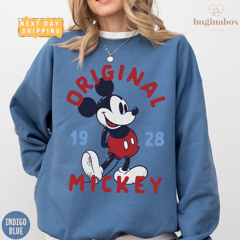 A woman wearing a blue sweatshirt with a graphic of Mickey Mouse printed on it.