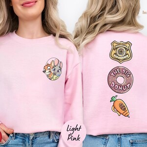 A woman wearing a pink sweatshirt with cartoon characters and a donut on the back.