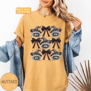 a woman wearing a mustard colored shirt with raccoon on it