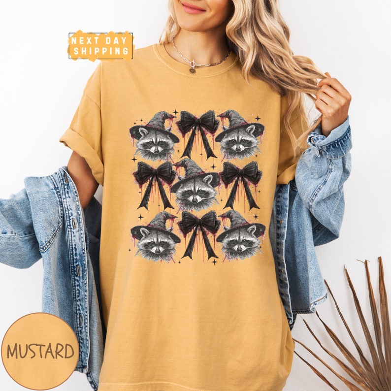 a woman wearing a mustard colored shirt with raccoon on it