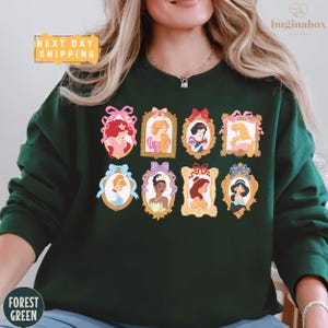 A woman wearing a green sweater with a collage of Disney princess portraits on it.