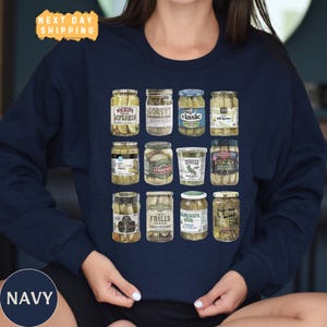 a woman wearing a navy blue shirt with a picture of jars of pickles on