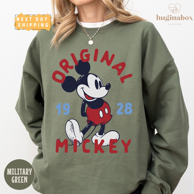 A woman wearing a green sweatshirt with a graphic of Mickey Mouse and text that says "ORIGINAL MICKEY".