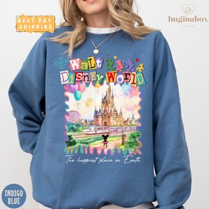 A woman wearing a blue sweatshirt with a colorful graphic of Walt Disney World and the text "The happiest place on Earth" printed on it.