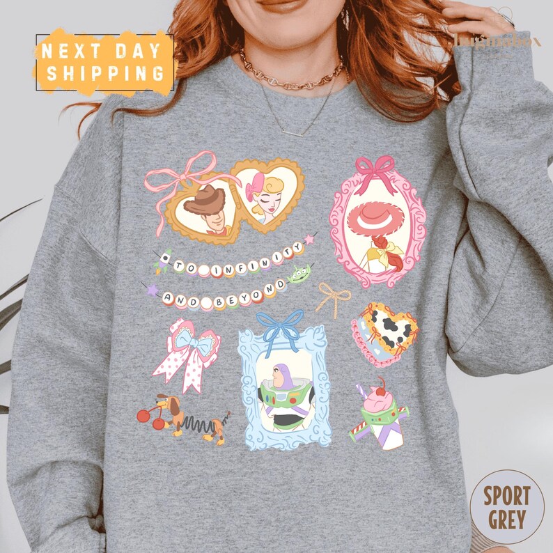 A person wearing a gray sweatshirt with various cartoon-style illustrations and text on it.
