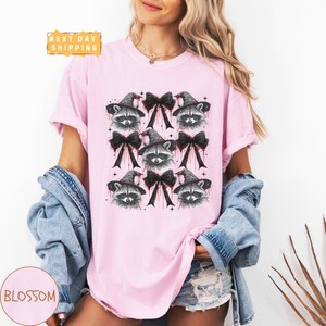 a woman wearing a pink shirt with a raccoon on it