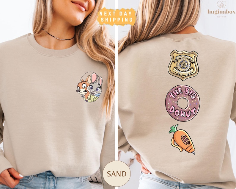 a woman wearing a beige sweater with various cartoon-style logos and designs on the back.