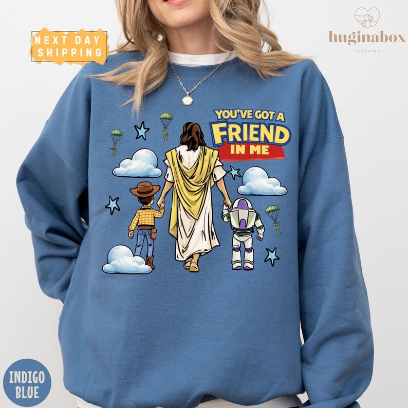 A blue sweatshirt with a cartoon illustration of a person holding a Bible and two children, along with the text "You've got a FRIEND in me" and a Bible character.