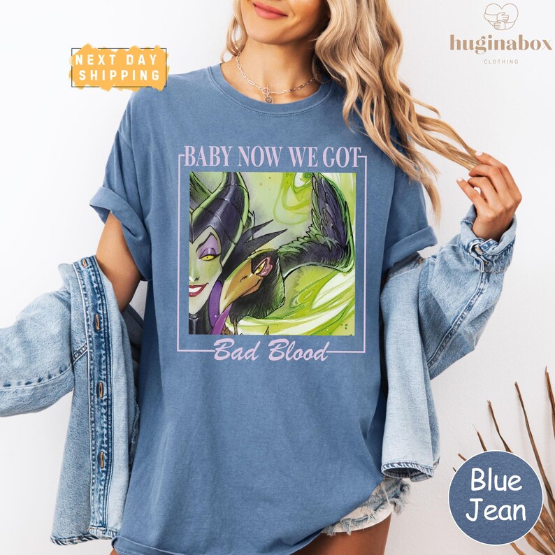 A woman wearing a blue t-shirt with a graphic design and text, posing with her hair in her hair.