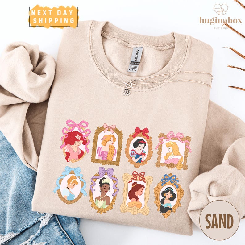 A beige sweatshirt with a graphic design featuring illustrations of various Disney princesses.