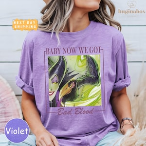 A woman wearing a purple t-shirt with a graphic design featuring a character from the Disney film "Bad Blood".