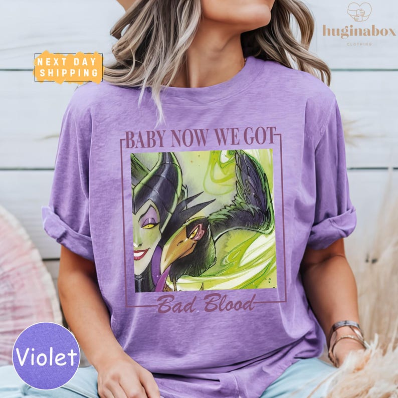 A woman wearing a purple t-shirt with a graphic design featuring a character from the Disney film "Bad Blood".