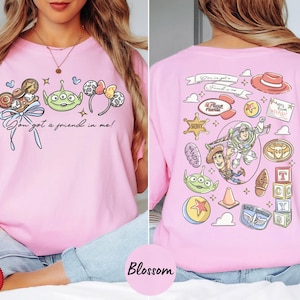 A woman wearing a pink t-shirt with various cartoon characters and icons printed on it, including a character from the Toy Story franchise.